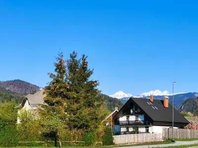 a house with a tree and mountains in the background at Deerwood Villa-Modern cozy 2br apartment with castle view in Bled