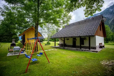 a playground in front of a building with a house at Počitniška hiša Taler in Bohinj