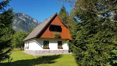 a small white and orange house in a field at Počitniška hiša Taler in Bohinj