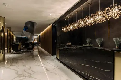 a lobby with a black counter and chandeliers at Hotel A plus in Celje