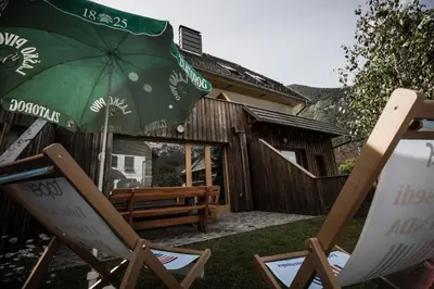 a patio with a bench and a green umbrella at APARTMENT ALPIN BOVEC in Bovec