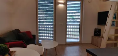 a living room with two large windows and a couch at Vila Mojca - Studio 13 in Kranjska Gora