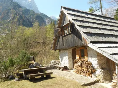 a cabin in the mountains with a pile of wood at Cottage Trenta in Bovec