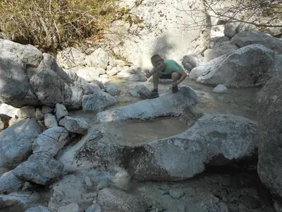 a man sitting on a rock in a stream of water at Cottage Trenta in Bovec