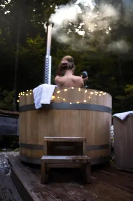 a man taking a bath in a wooden tub at Cottage Trenta in Bovec