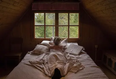 a person laying in bed in a room with a window at Cottage Trenta in Bovec