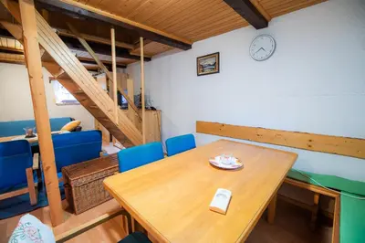 a dining room with a wooden table and blue chairs at Hiska Rutar Valley Voje in Studor v Bohinju