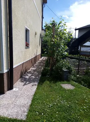 a sidewalk next to a building with a small tree at Apartma Rutar in Tolmin