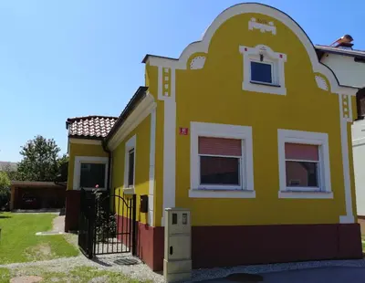 a yellow house with a white window and a gate at Apartment Kokoro in Bogojina