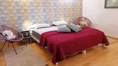 a bedroom with a bed with a red blanket and two chairs at Apartment Kokoro in Bogojina