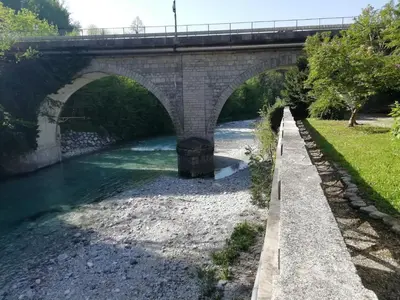 a stone bridge over a river with a river at Apartma Humar in Tolmin