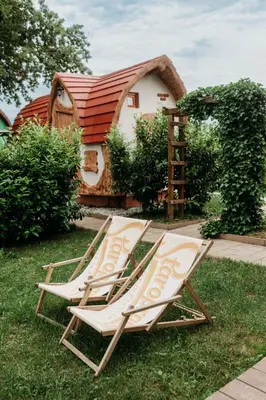 two lounge chairs sitting on the grass in front of a house at Glamping Rajska vas in Šentjur