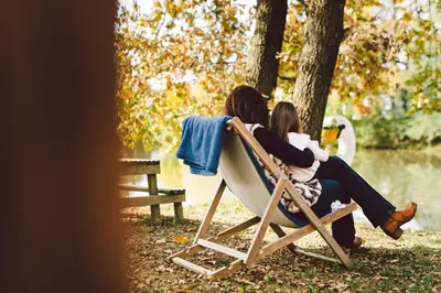 two women sitting in a chair by the water at Glamping Rajska vas in Šentjur