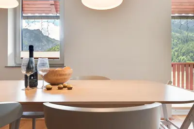 a dining room table with a bottle of wine and two glasses at Villa Planina in Rateče