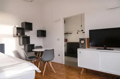 a white bedroom with a tv and a table and chairs at Modern studio in the heart of the city in Maribor
