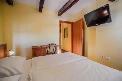 a bedroom with a bed with a tv on the wall at Bed & Breakfast Šilak in Ptuj