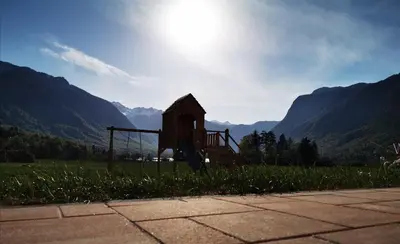 a playground in a field with mountains in the background at Apartment Jezero Lake Bohinj in Bohinj