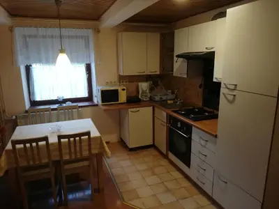 a kitchen with white cabinets and a table and a refrigerator at Apartment Sopar in Škofja Loka