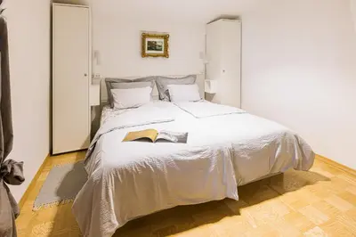 a bedroom with a large white bed with a book on it at Quercus Apartments Bled in Bled