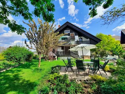 a house with chairs and an umbrella in the yard at Deerwood-Large Villa relax with castle view in Bled