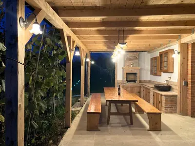 an outdoor kitchen with a wooden table and benches at Papa Franks House in Ptuj