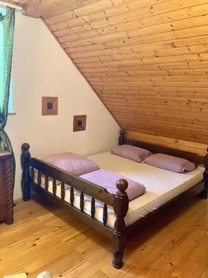a bed in a room with a wooden ceiling at Papa Franks House in Ptuj