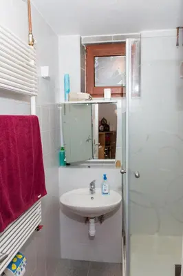 a white bathroom with a sink and a shower at Brunarica Čontoš in Lendava
