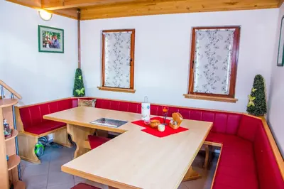 a red booth with a wooden table and red chairs at Brunarica Čontoš in Lendava