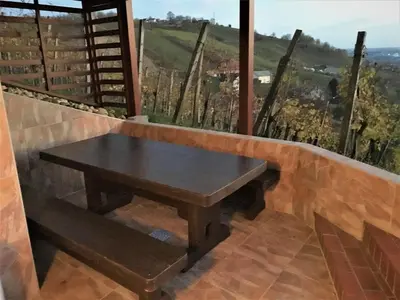 a wooden bench in front of a window with a table at Brunarica Čontoš in Lendava
