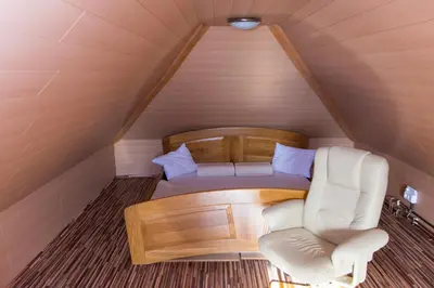a room with a couch and a chair in a attic at Brunarica Čontoš in Lendava