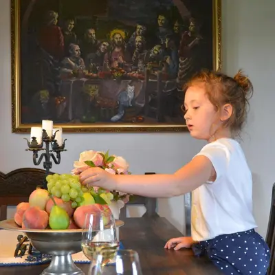 a little girl sitting at a table with a bowl of fruit at Vinum Vidae in Lendava
