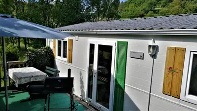 a white cabin with green doors and a table at Holiday home Rozika in Slovenj Gradec