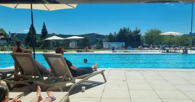 a group of people sitting in chairs near a swimming pool at Holiday home Rozika in Slovenj Gradec
