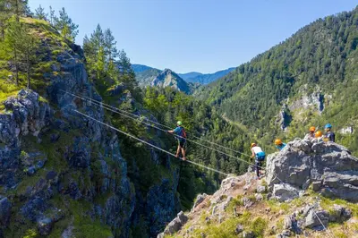 a group of people walking on a rope bridge in the mountains at Holiday home Rozika in Slovenj Gradec