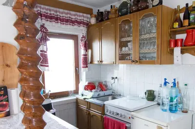 a kitchen with wooden cabinets and a white counter top at Pri konjskem pajdašu in Lendava
