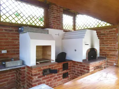 a brick fireplace with a pizza oven in a room at Vila Tamaškut in Lendava