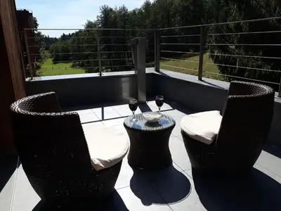 two chairs and a table with wine glasses on a balcony at Apartments Maleric with Indoor Pool and Wellness in Dragatuš