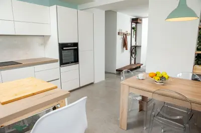 a kitchen with white cabinets and a table with a bowl of fruit at Hiška pod Krasom in Renče