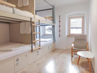 a room with bunk beds and a chair and a table at Hostel Kobarid in Kobarid