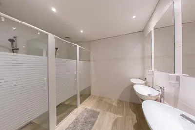 a white bathroom with two toilets and a shower at Hostel Kobarid in Kobarid