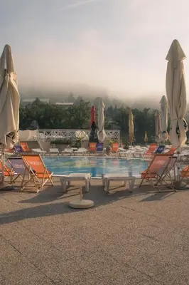 a pool with chairs and tables and umbrellas at Hotel Aqua Roma in Rimske Toplice