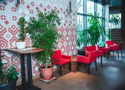 a restaurant with red chairs and plants on a wall at Bed and Breakfast Portal in Ljubljana