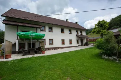 a large white building with a green umbrella outside at Apartma Vidmar Otlica in Ajdovščina