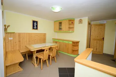 a kitchen with wooden cabinets and a table and chairs at Apartma Vidmar Otlica in Ajdovščina