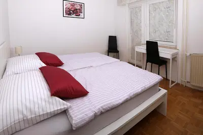 a white bed with red pillows in a bedroom at Apartma Dolinar in Gorenja Vas