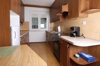 a kitchen with wooden cabinets and a white refrigerator at Apartma Dolinar in Gorenja Vas