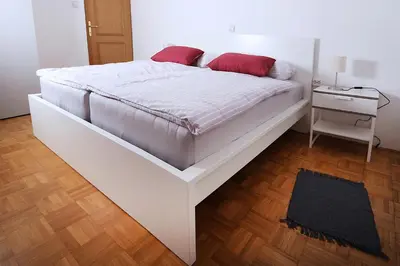 a white bed with red pillows on it in a room at Apartma Dolinar in Gorenja Vas