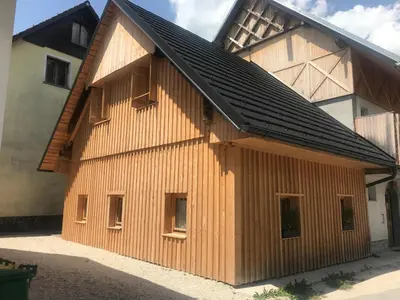 a large wooden building with a black roof at LAKE HOUSE BOHINJ in Bohinj
