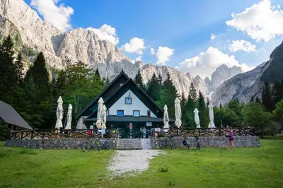 a house in a field with mountains in the background at Apartments Julian Adventure in Kranjska Gora