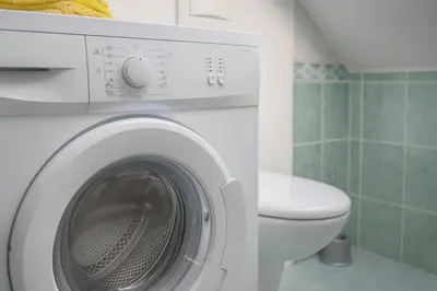 a white washing machine in a bathroom with a toilet at Sunset Apartments Bohinj in Bohinj